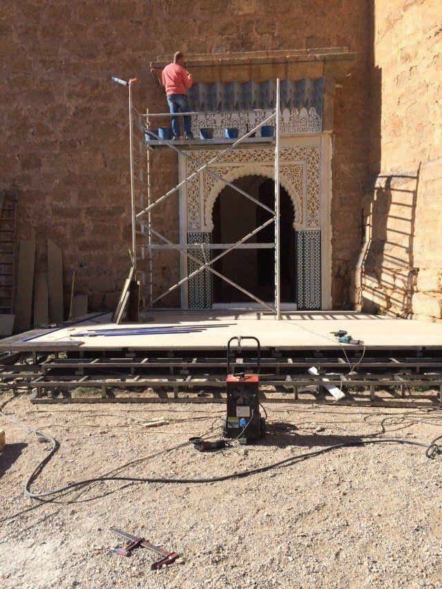 Un hombre está parado en un andamio frente a un edificio.
