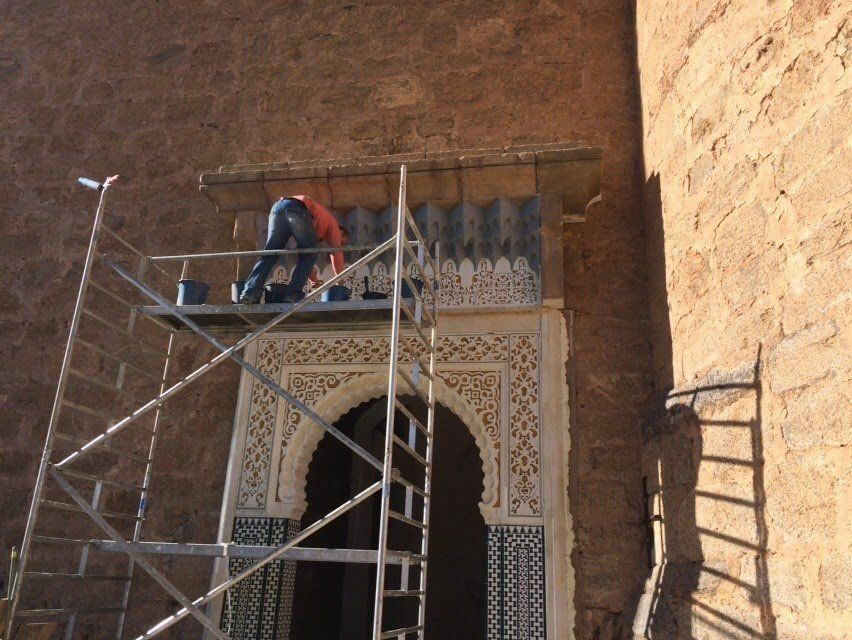 Un hombre está de pie en un andamio sobre un arco.