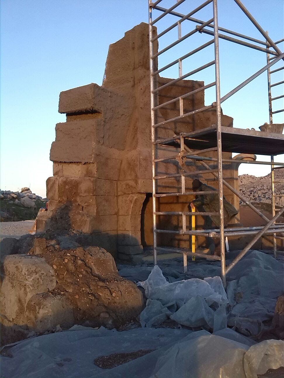 Un andamio delante de un gran muro de roca.