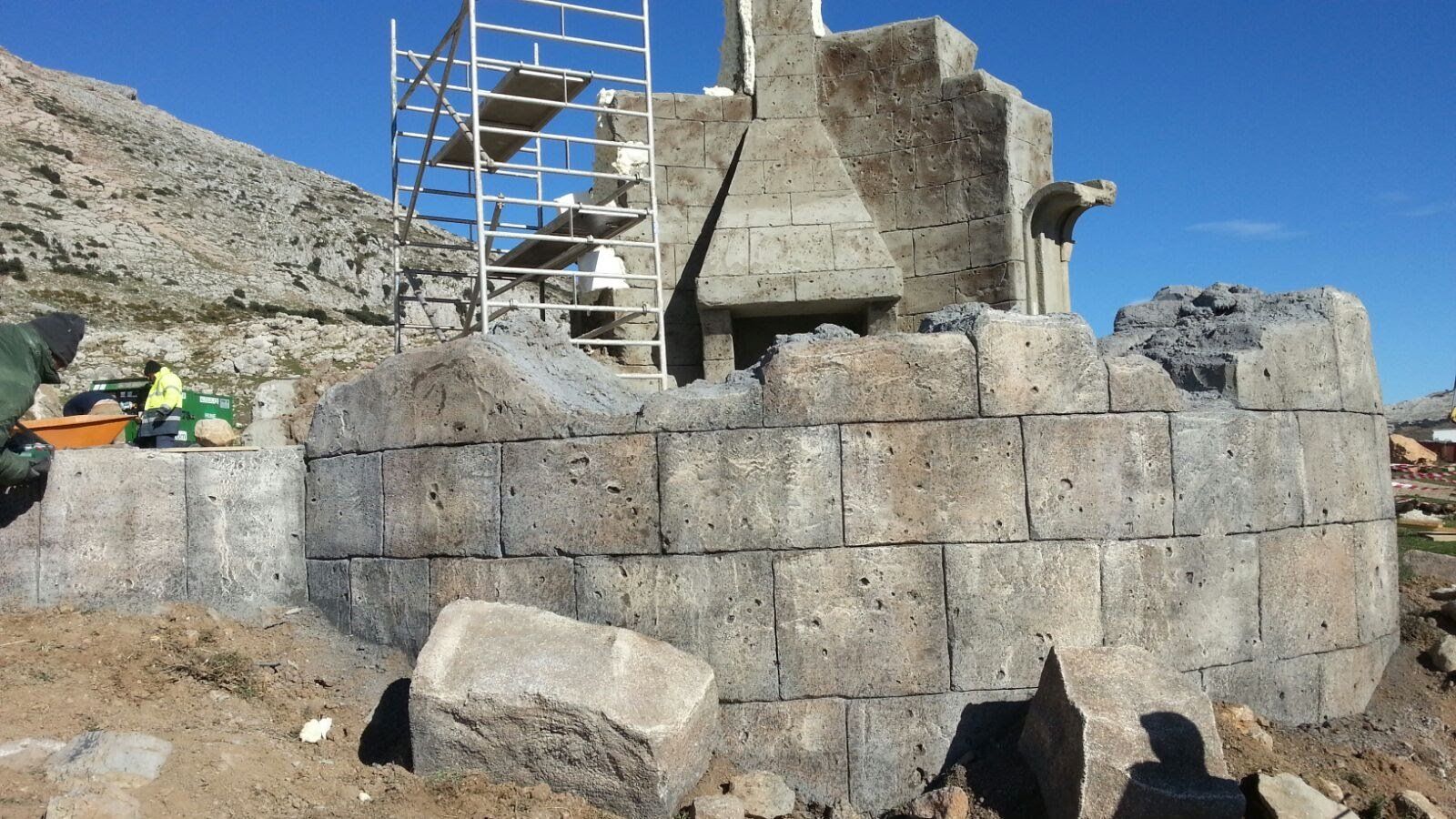 Un gran muro de piedra con un andamio al fondo.