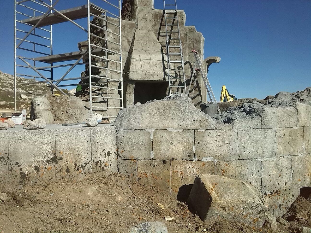 Se está construyendo un muro de hormigón con andamios al fondo.