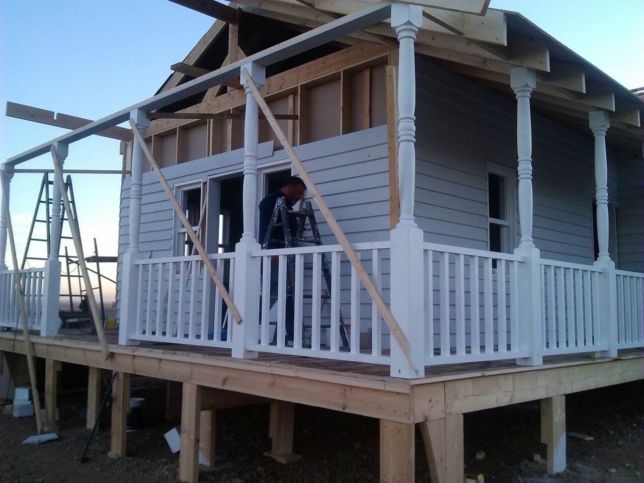 Un hombre está de pie en el porche de una casa en construcción.