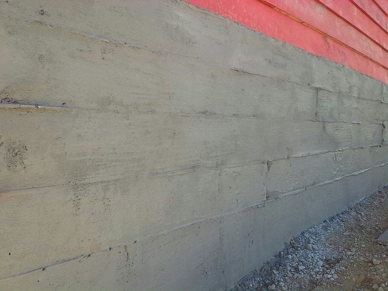 Un primer plano de un muro de hormigón al lado de un edificio rojo.