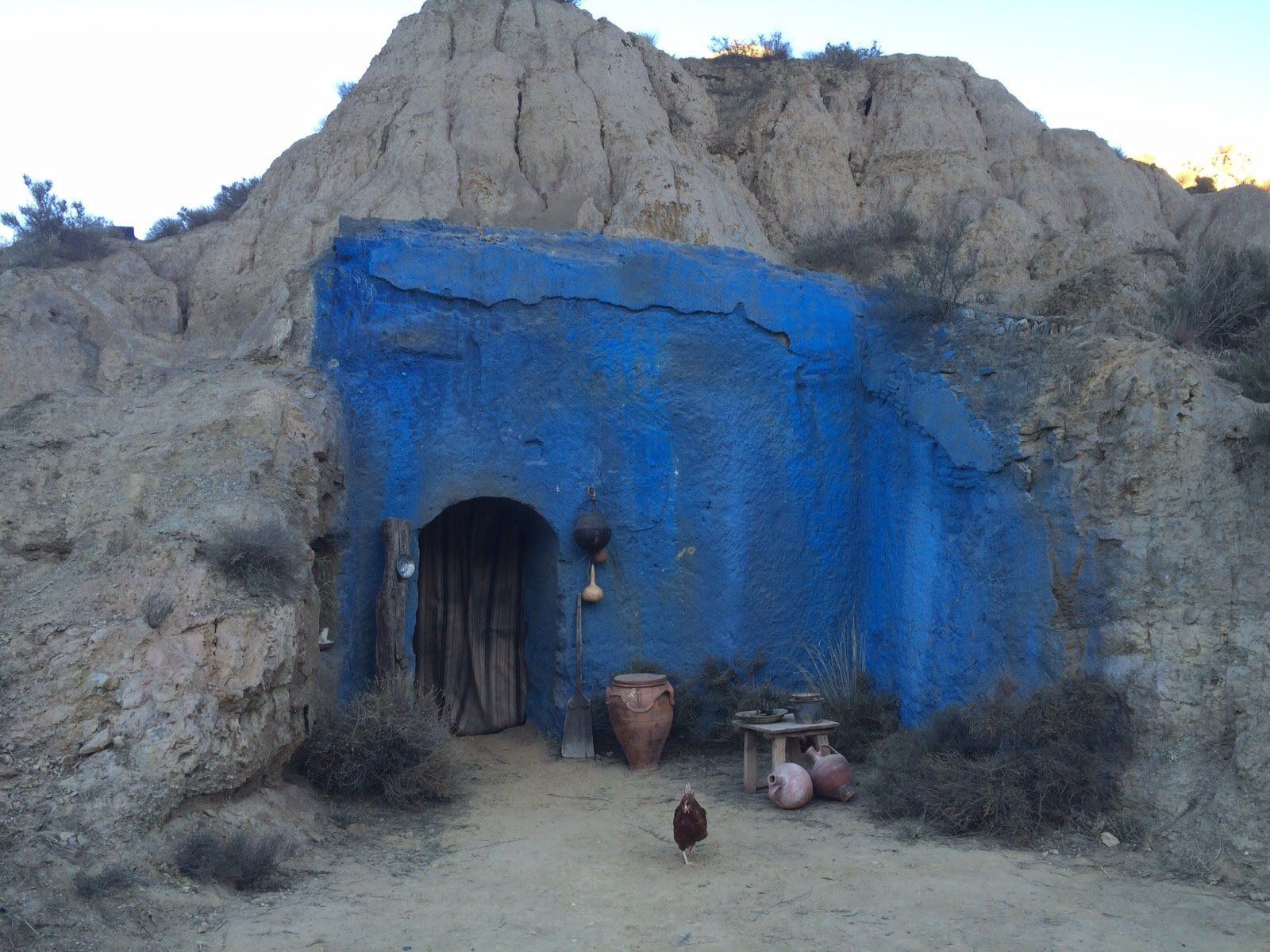 Un edificio azul con un pollo delante.