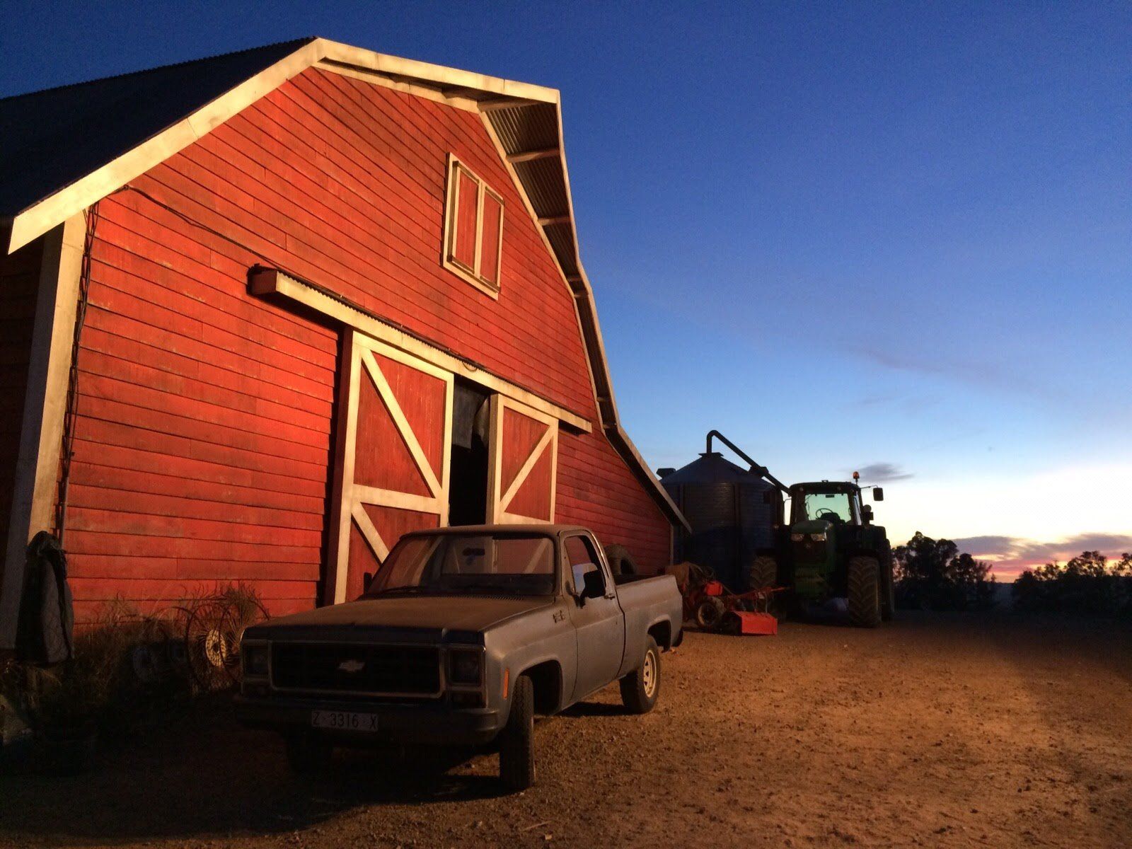 Un camión está estacionado frente a un granero rojo.