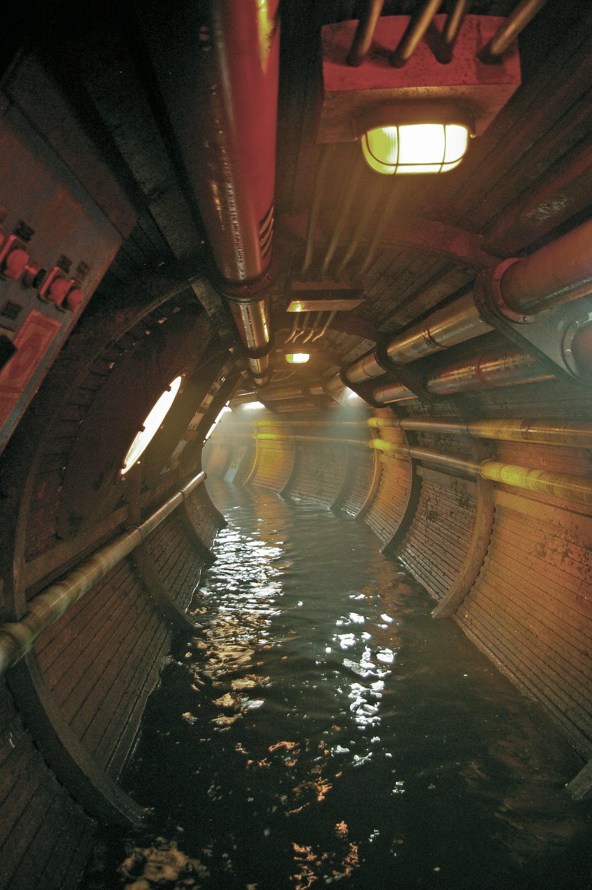 Un túnel con muchas tuberías y agua en él.