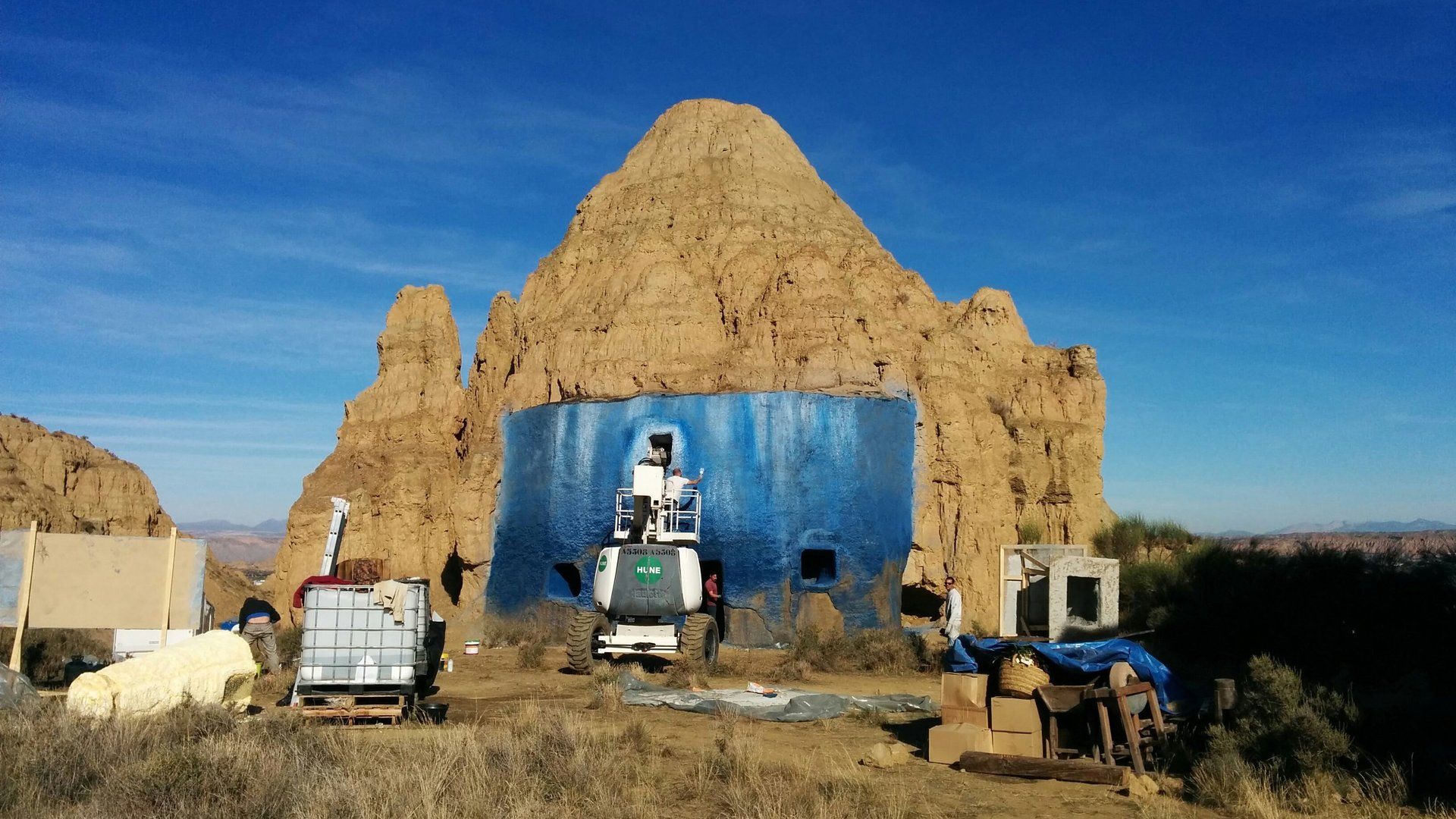 Una pared azul está pintada en el costado de un edificio en el desierto.