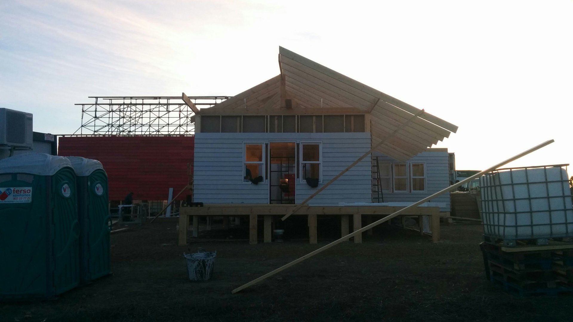 Se está construyendo una casa en un campo al lado de un baño portátil.