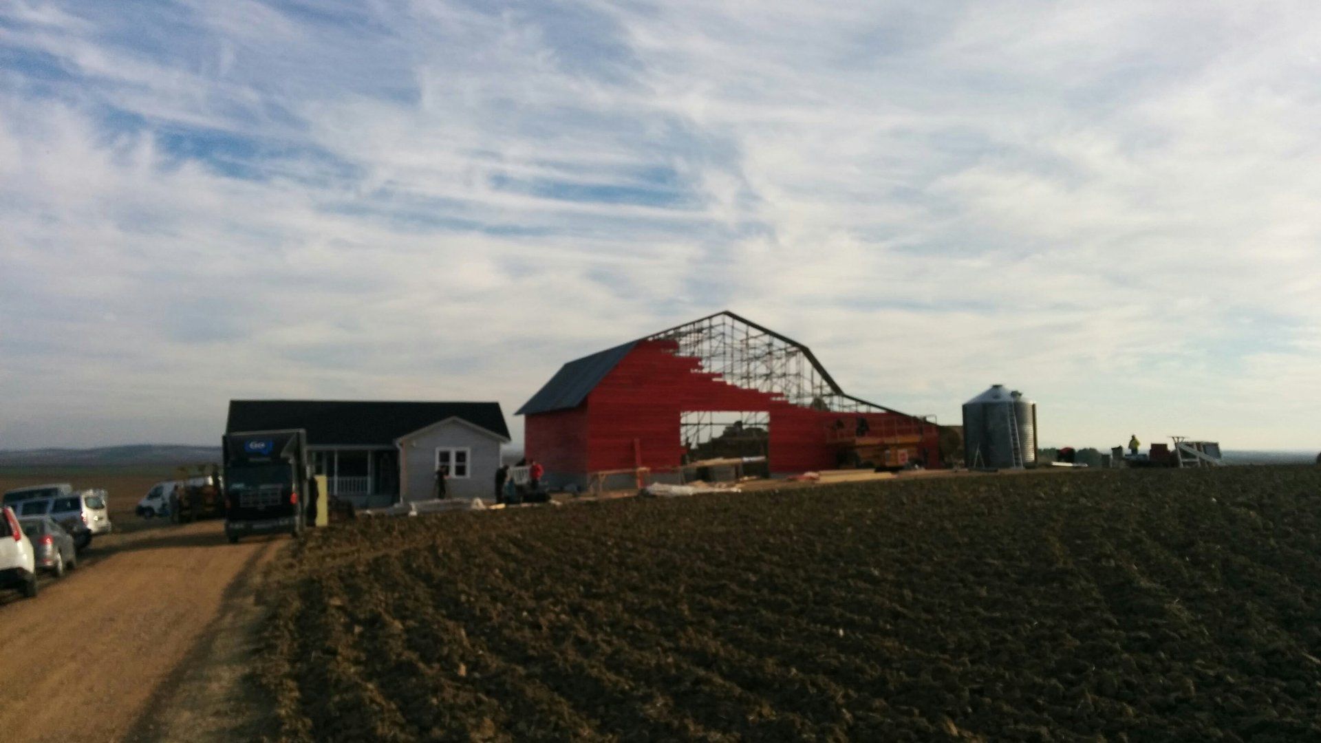 Se está construyendo un granero rojo en medio de un campo de tierra.