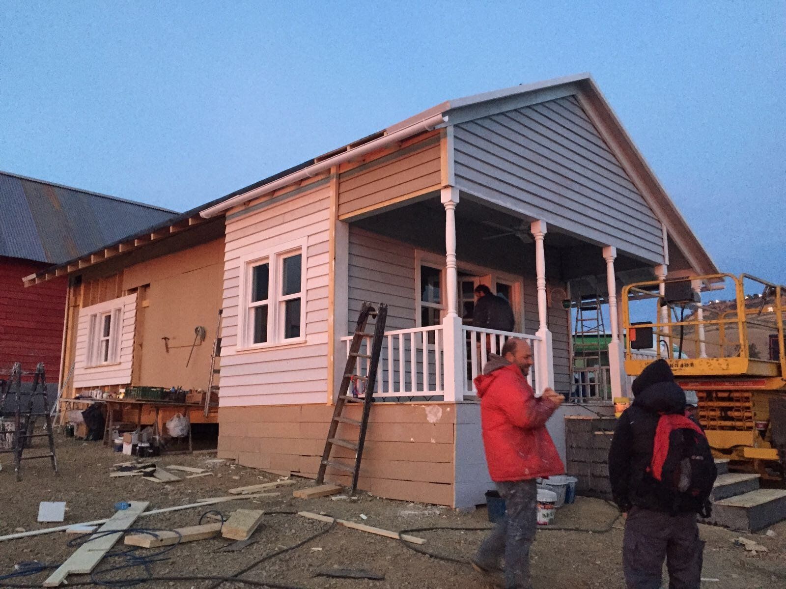 Un hombre con una chaqueta roja se encuentra frente a una casa en construcción.