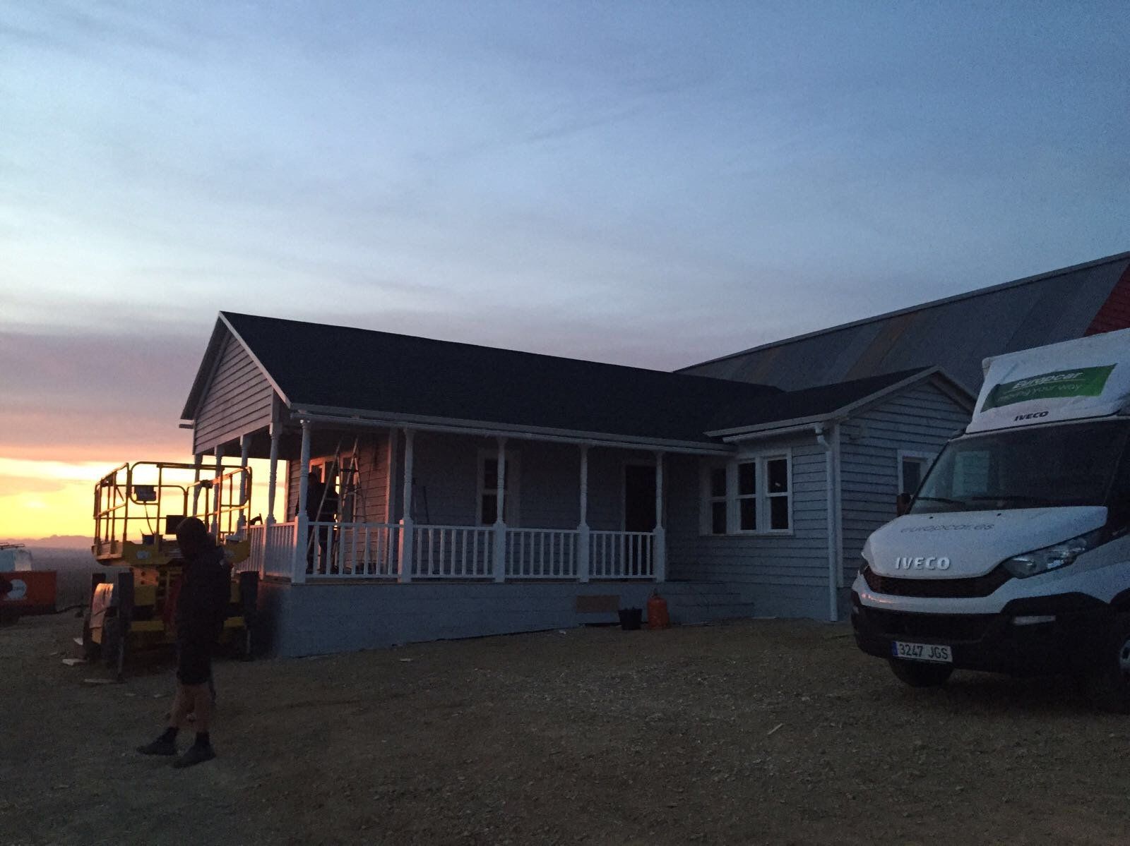 Una camioneta blanca está estacionada frente a una casa al atardecer.