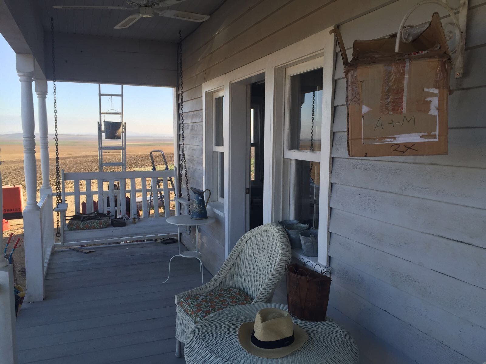 Un porche con una silla y un sombrero encima.