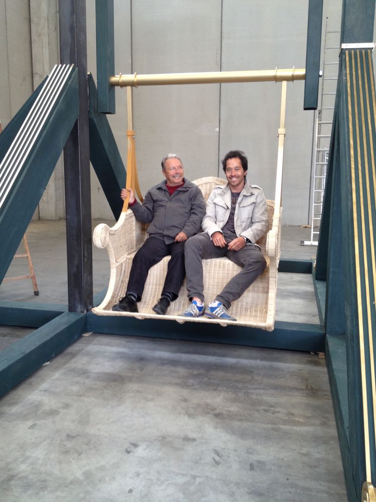 Dos hombres están sentados en un columpio de mimbre en un almacén.