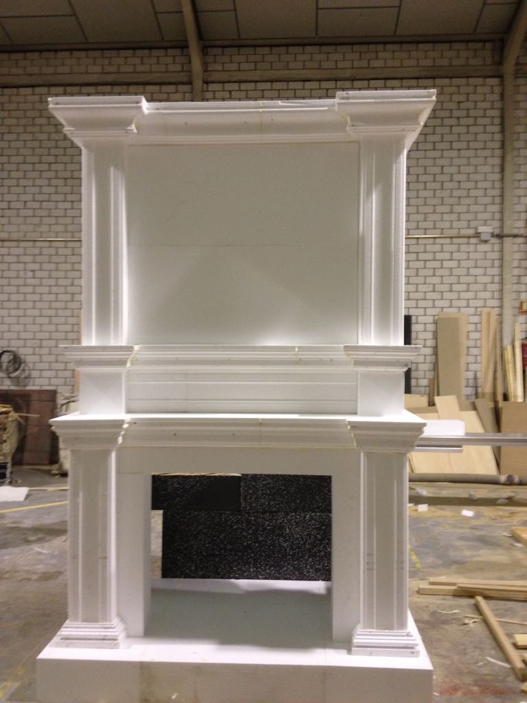 Una chimenea blanca se encuentra en un almacén al lado de una pared de ladrillos.