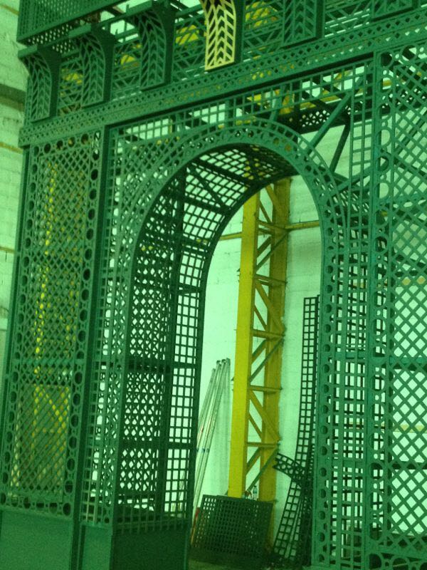 Un arco verde en un edificio con una grúa amarilla al fondo.