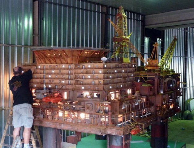 Un hombre está trabajando en un modelo de una plataforma petrolera.