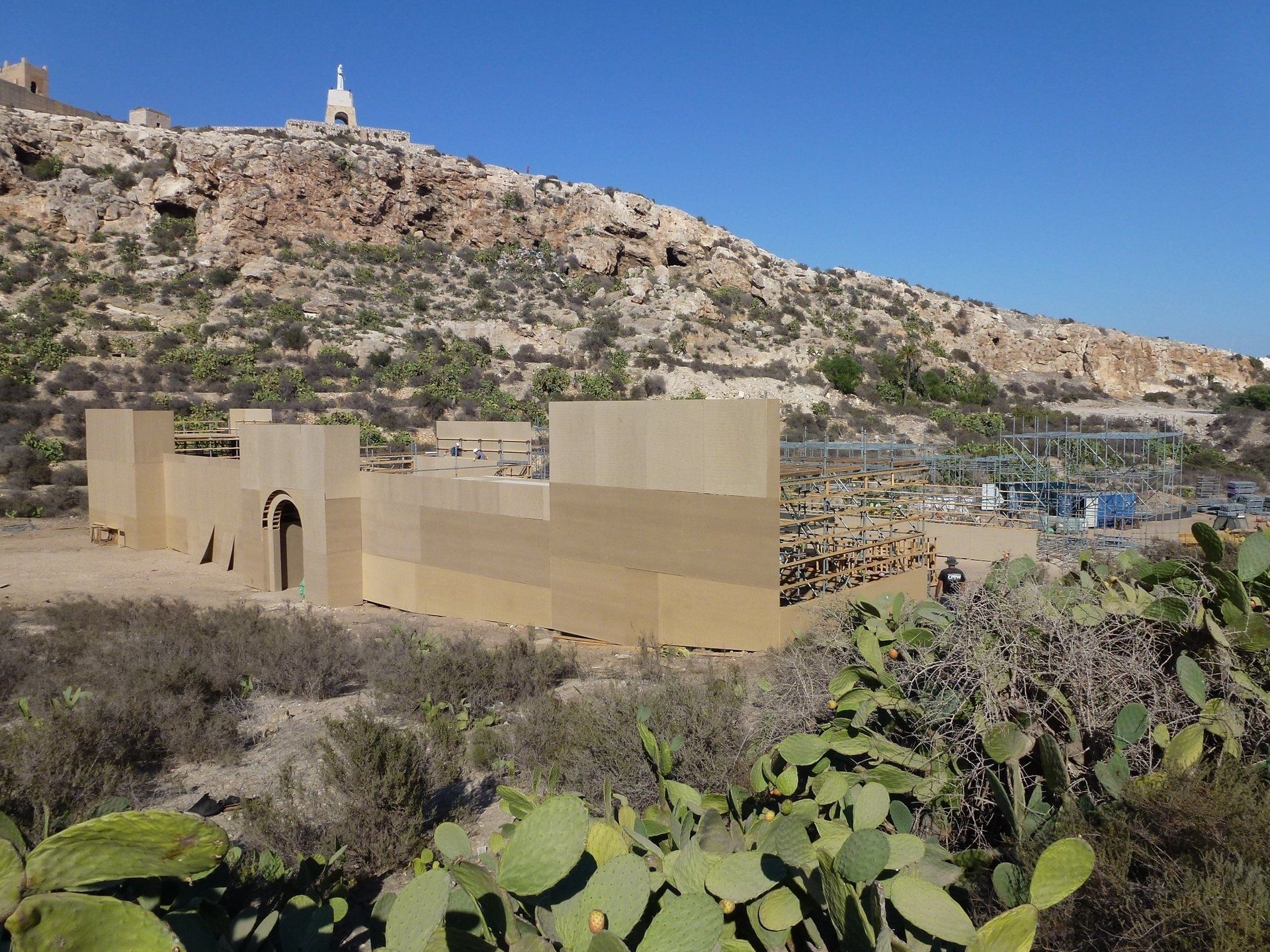 Un edificio en medio de un desierto con un cactus en primer plano.