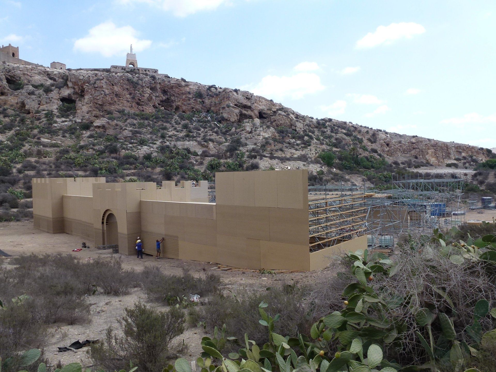 Un edificio en medio de un desierto con una montaña al fondo.