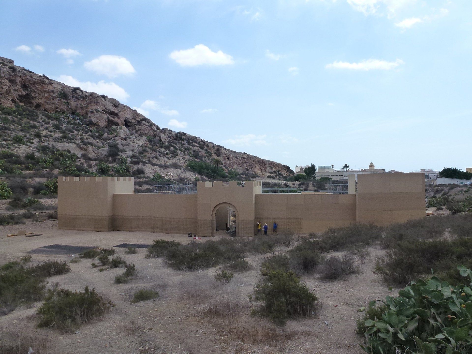 Un edificio en medio de un desierto con una montaña al fondo.