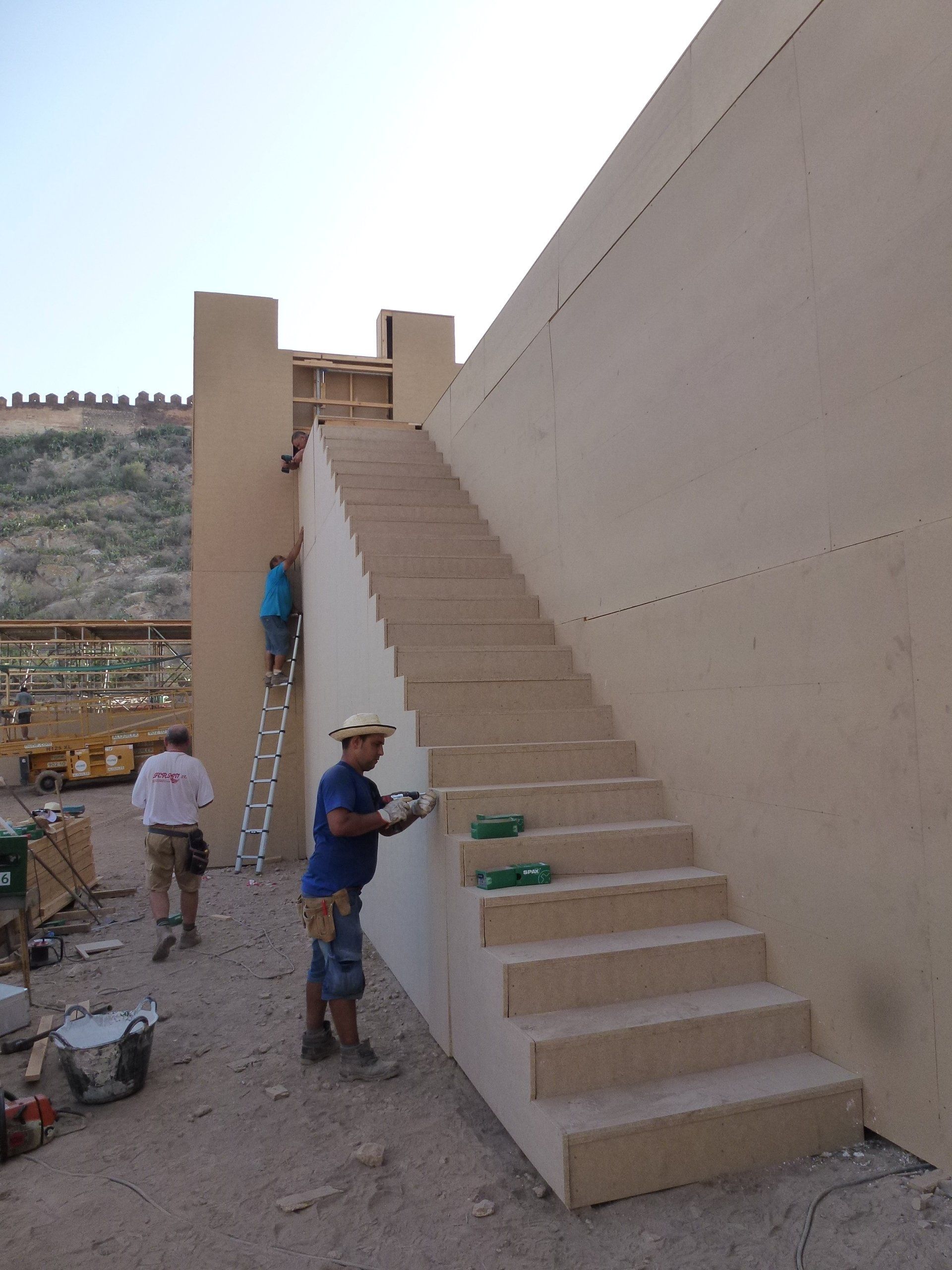 Un hombre con sombrero está pintando escaleras en una pared.
