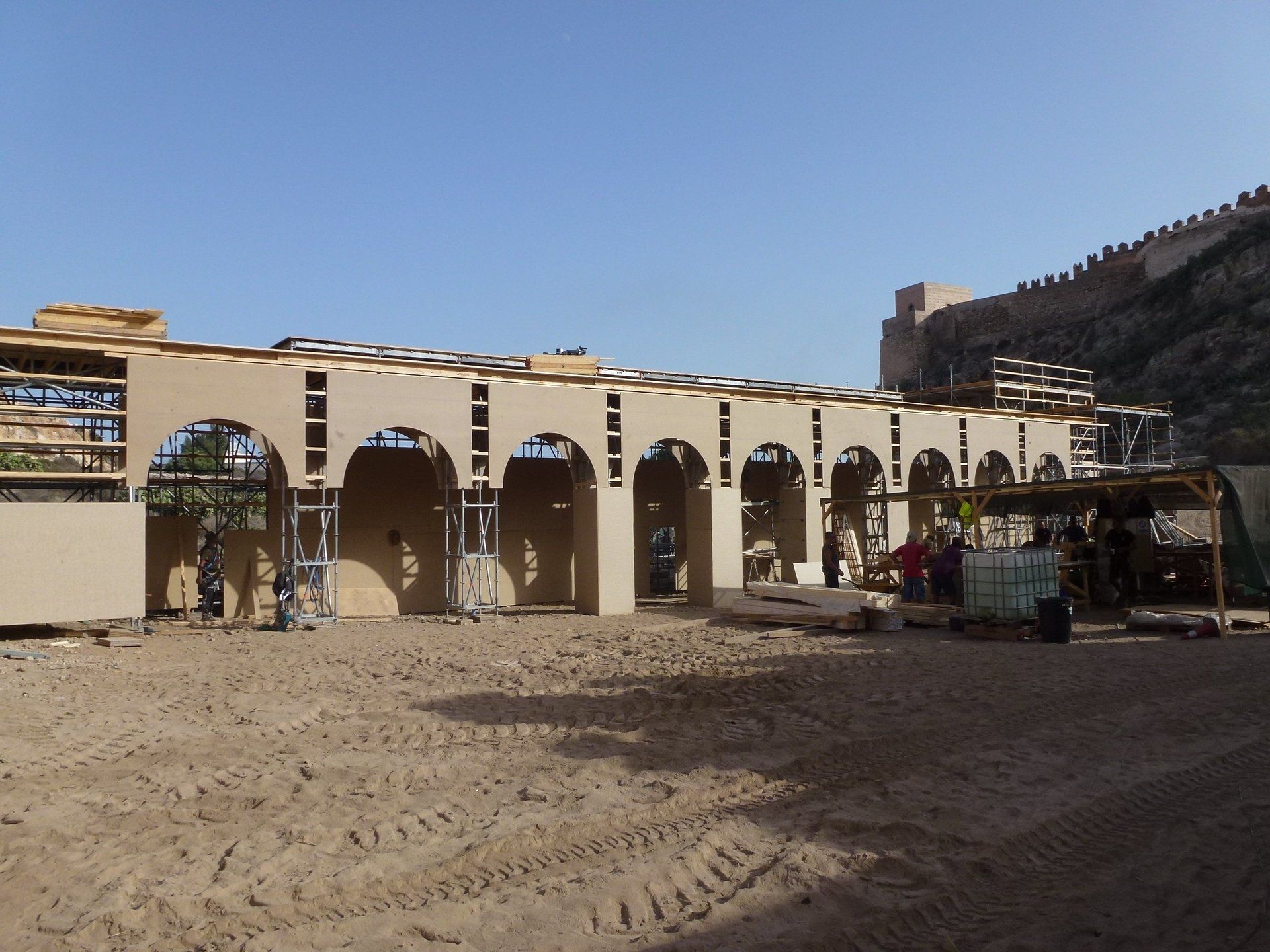 Un edificio en construcción con arcos y un castillo al fondo.