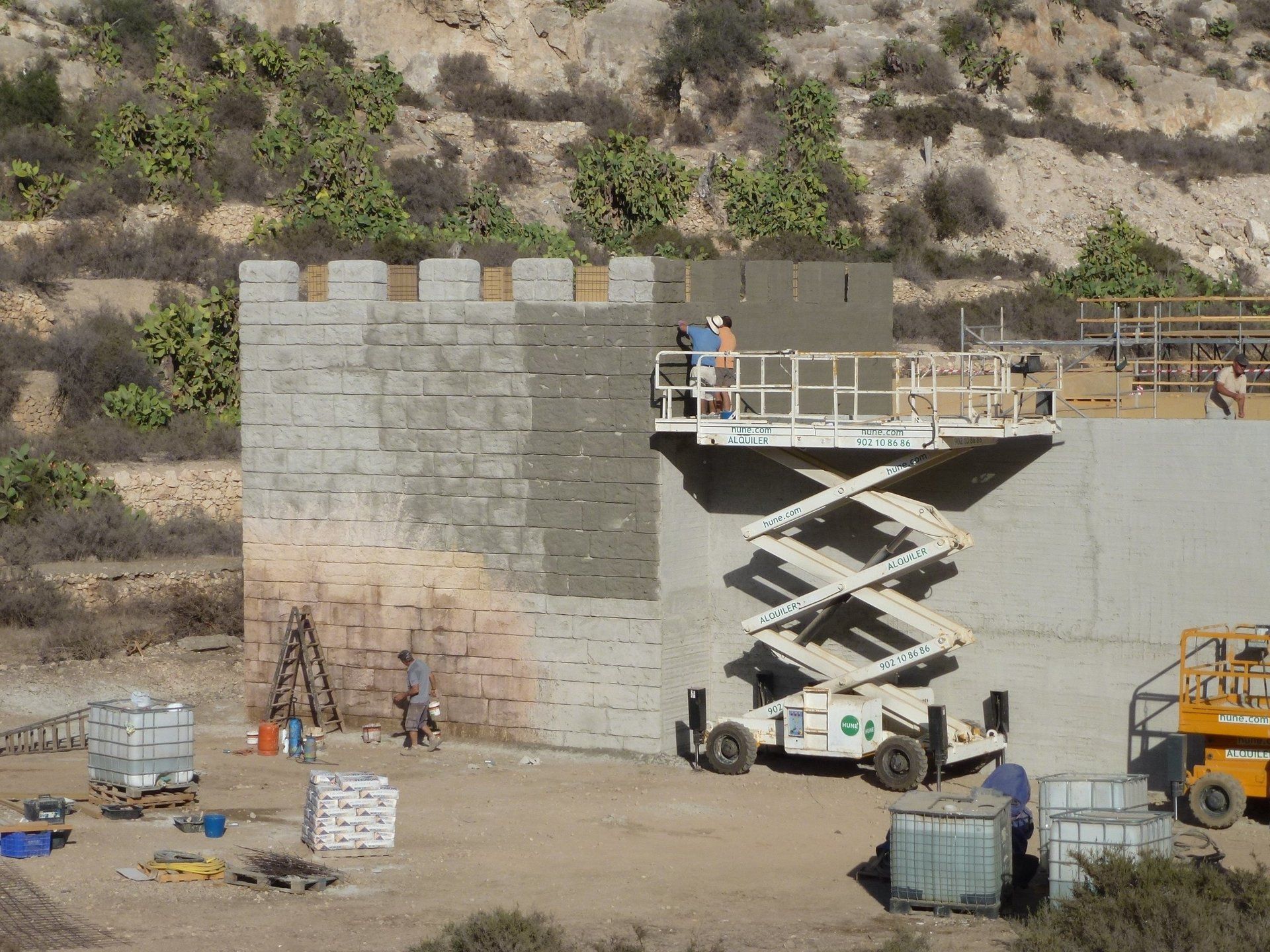 Una obra en construcción con un elevador de tijera en primer plano