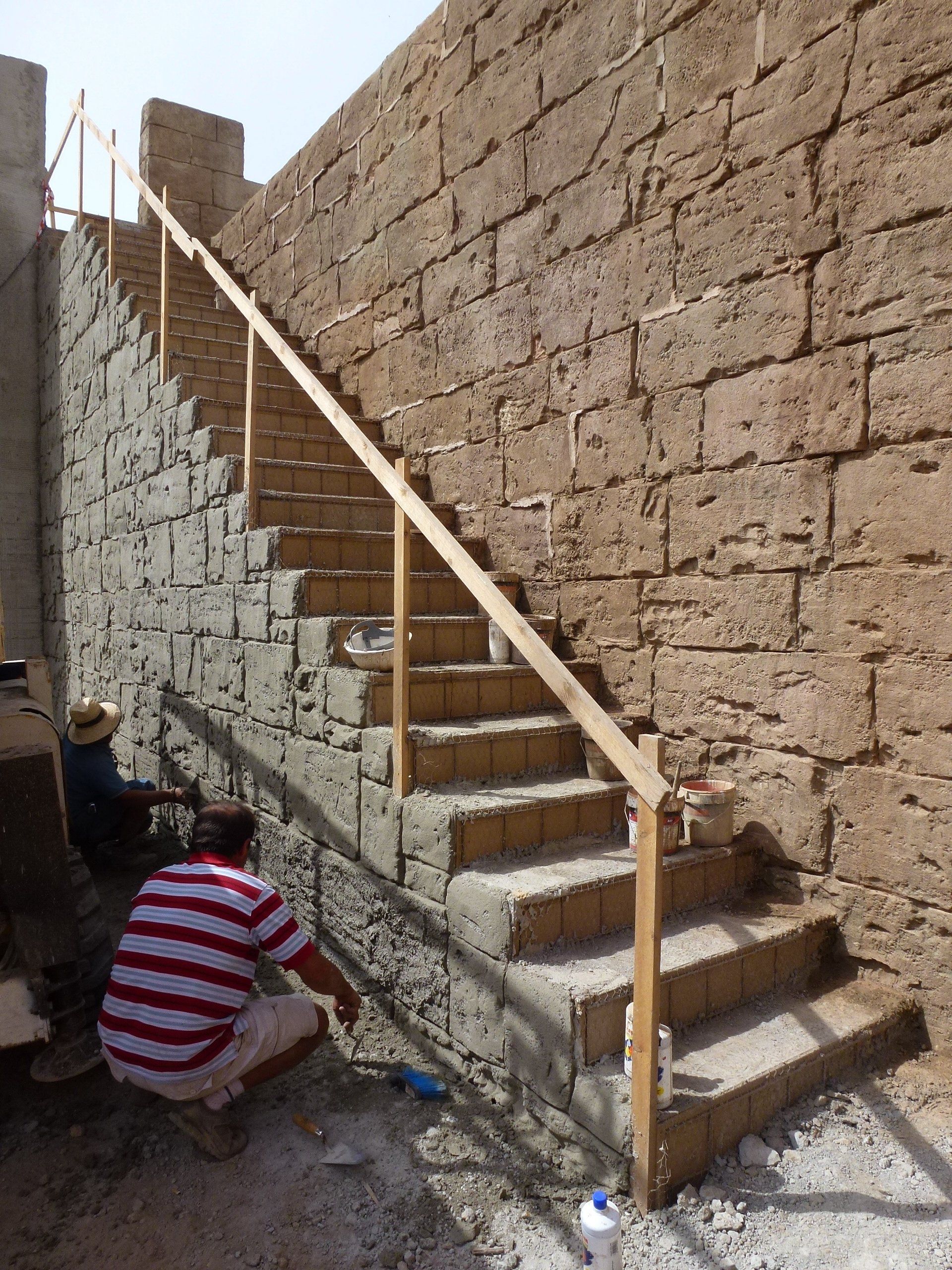Un hombre con una camisa a rayas está trabajando en un tramo de escaleras.