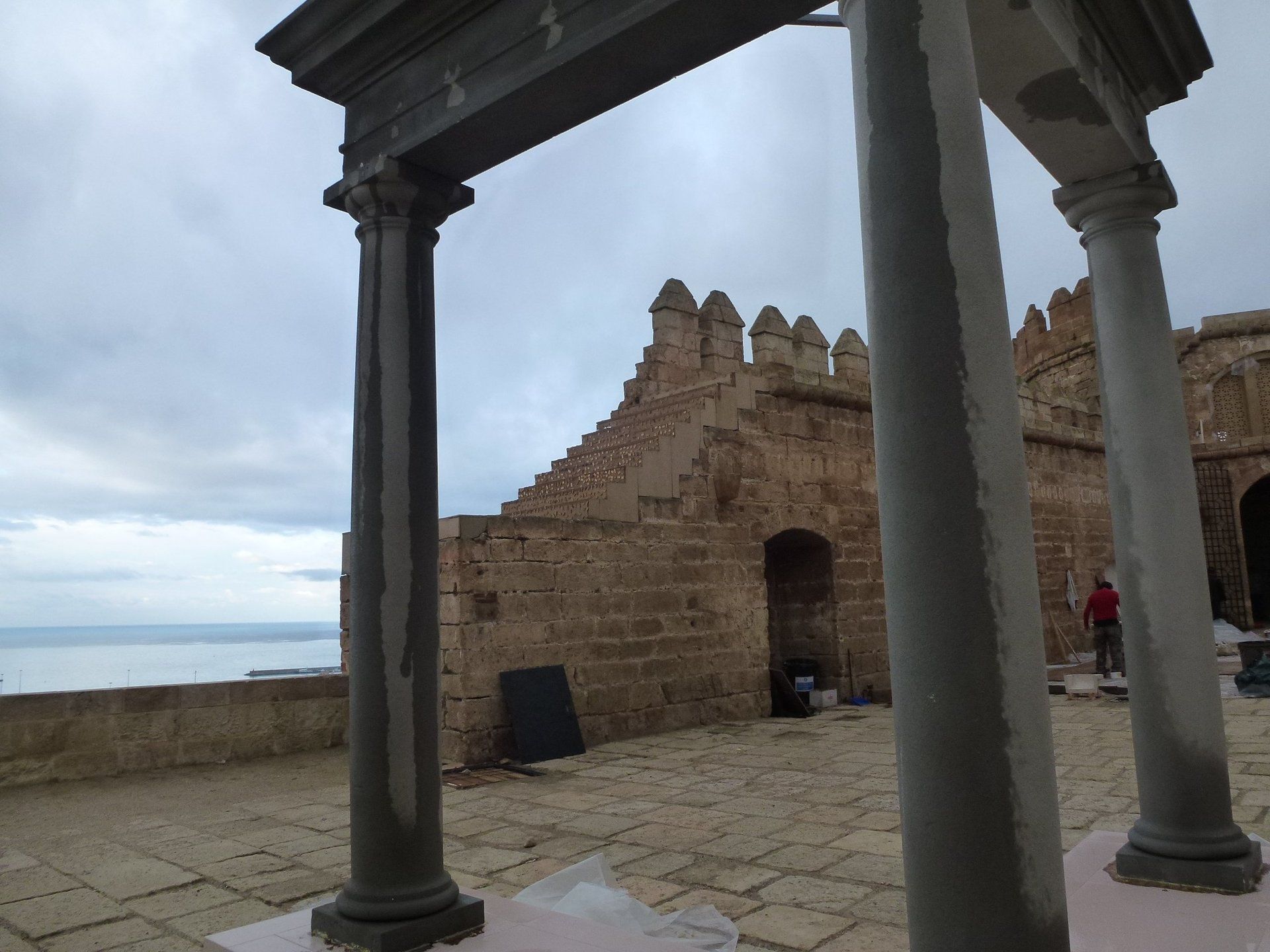 Un arco de piedra que conduce a un edificio con vista al océano.