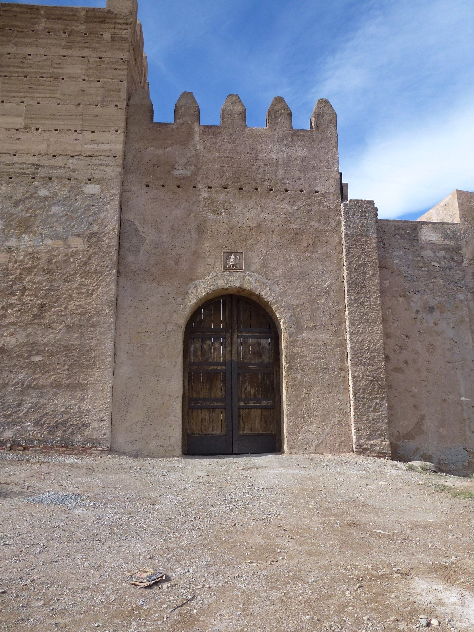 Un edificio de ladrillo con una puerta de madera y un cielo azul al fondo.
