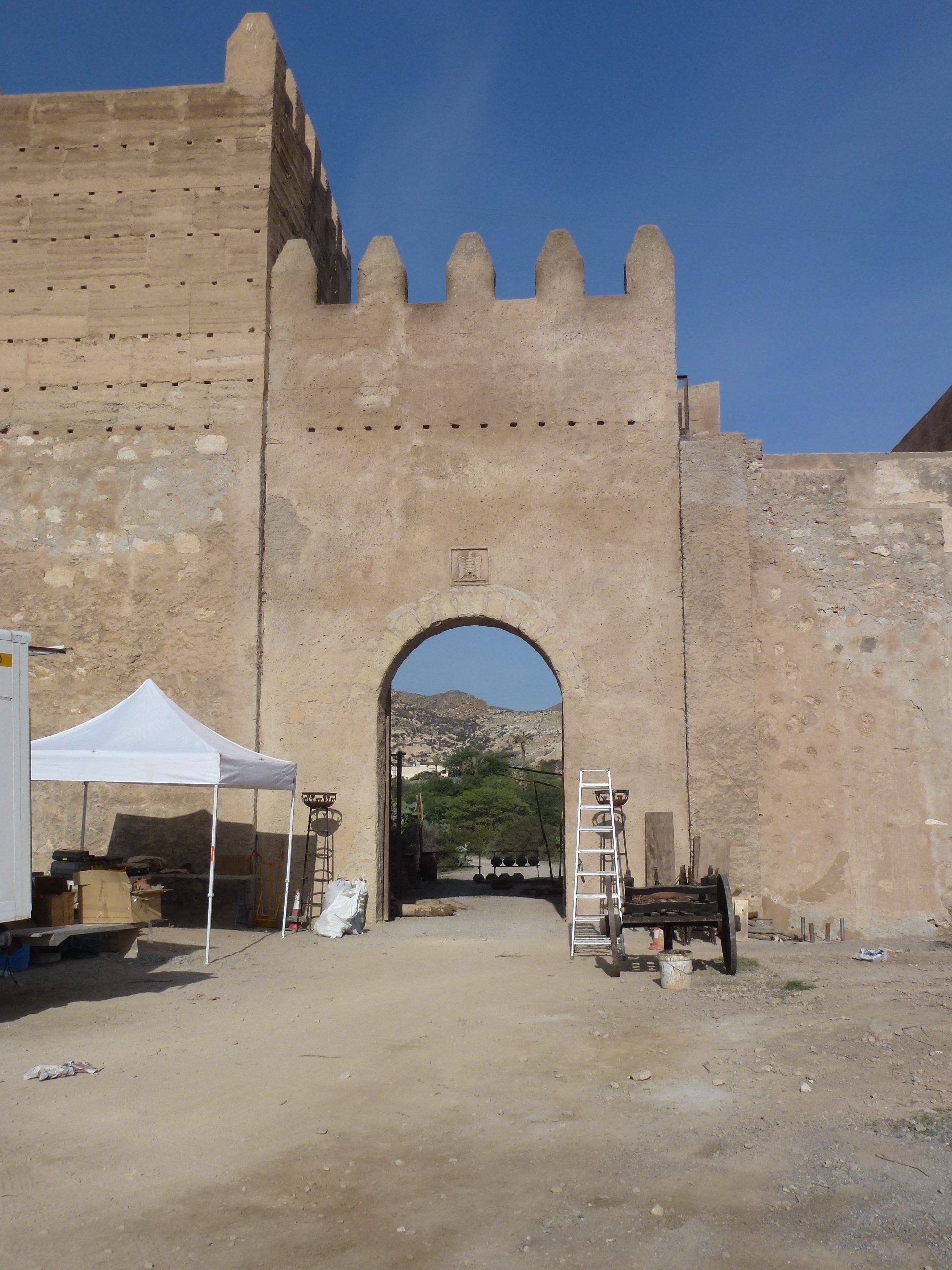 Una tienda de campaña blanca está situada frente a un muro de piedra.