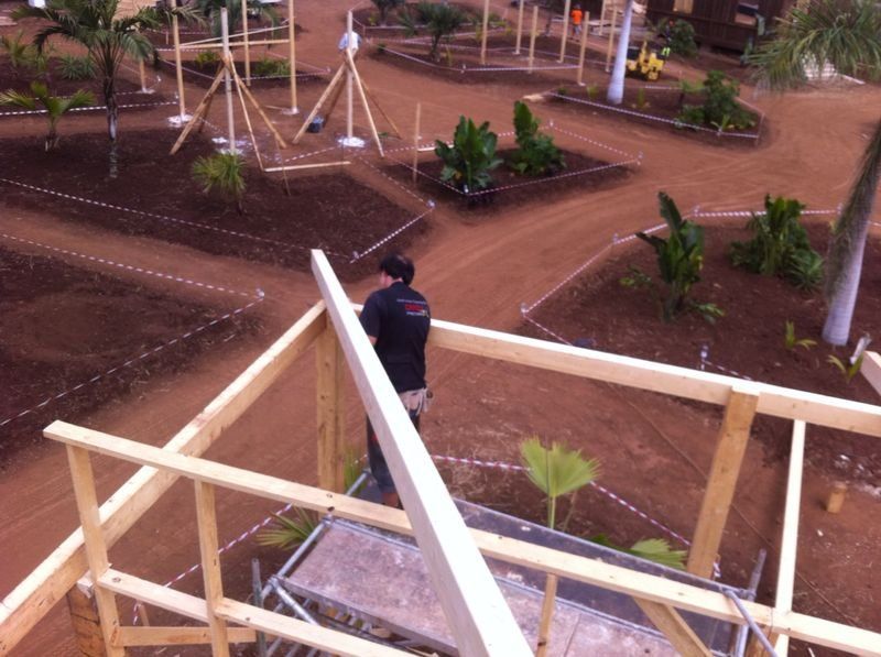 Un hombre está trabajando en una estructura de madera en un jardín.