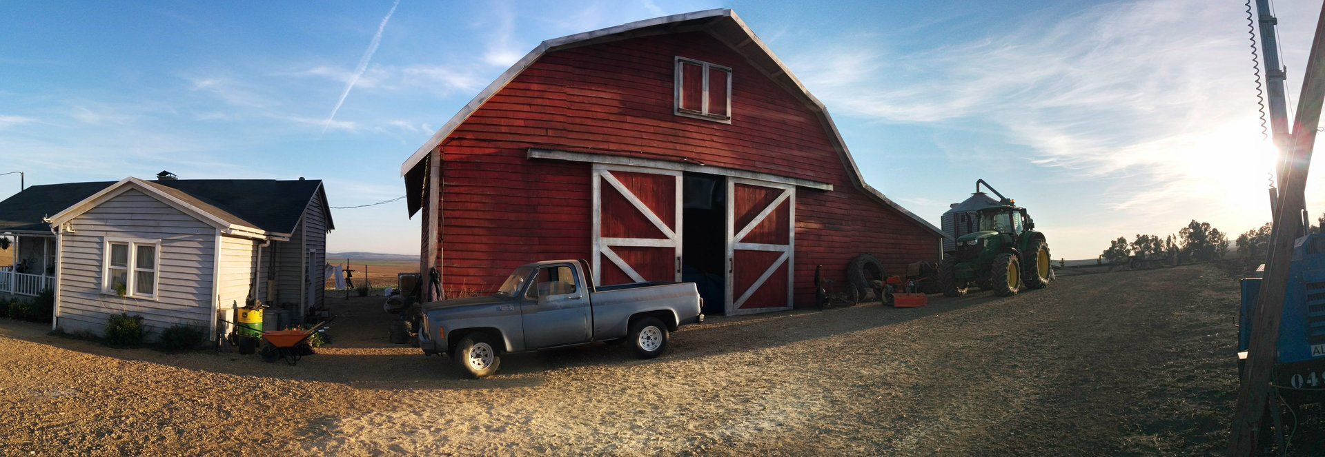 Un camión blanco está estacionado frente a un granero rojo.