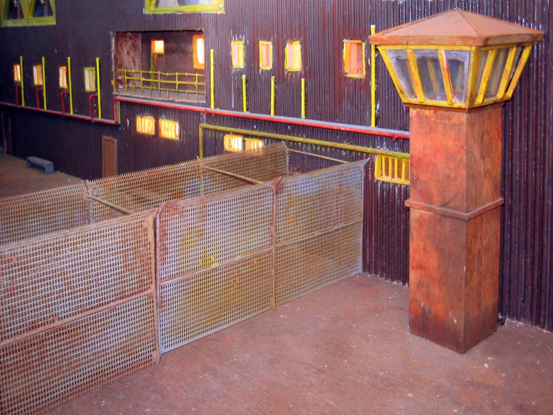 Un edificio con una valla y una torre delante.