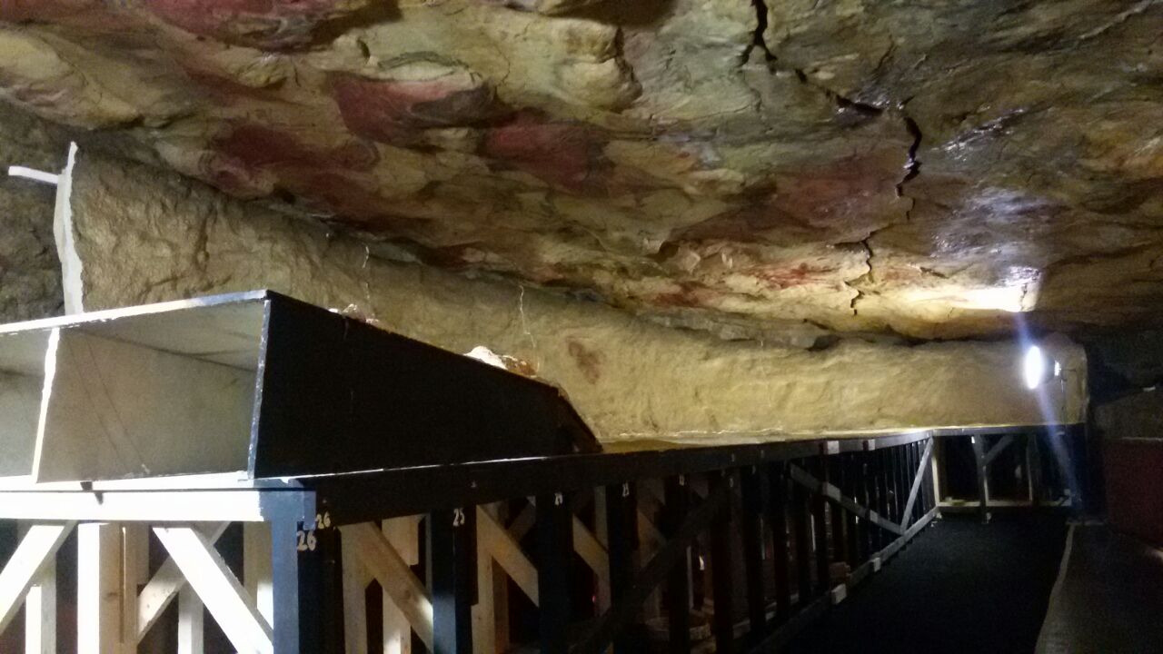 Una cueva con un estante y una pintura en el techo.