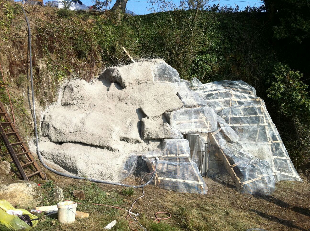 Una gran roca está cubierta de plástico y hay una escalera al fondo.