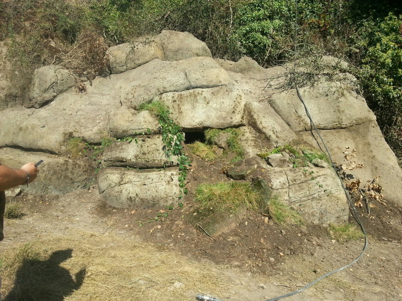 Una persona parada frente a una gran roca con un agujero en ella.