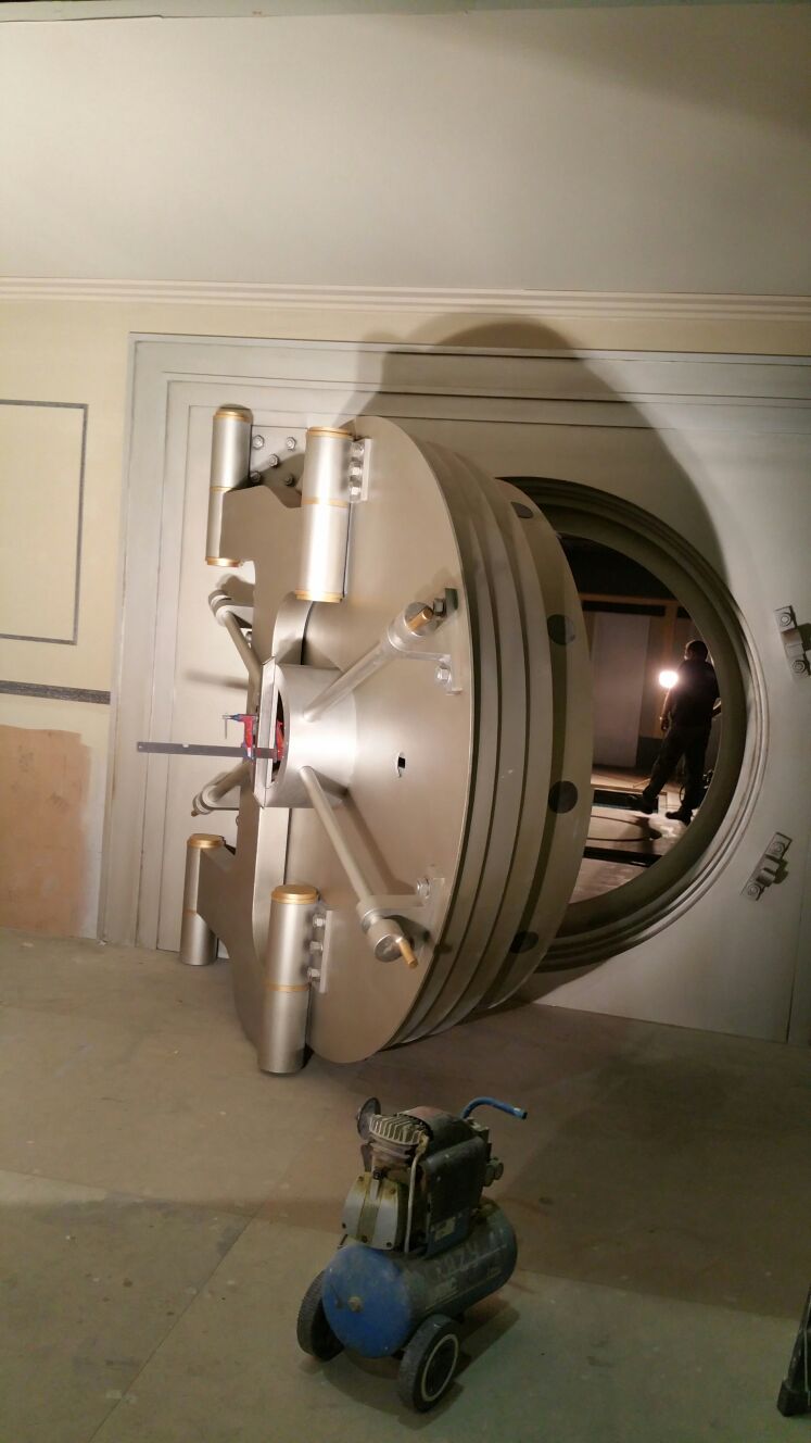 Una puerta de bóveda está abierta en una habitación con una aspiradora delante de ella.