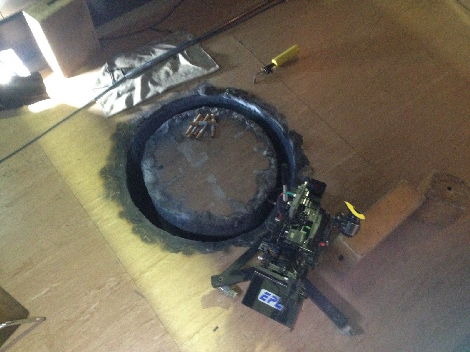 Un objeto circular está sobre un piso de madera junto a un destornillador.