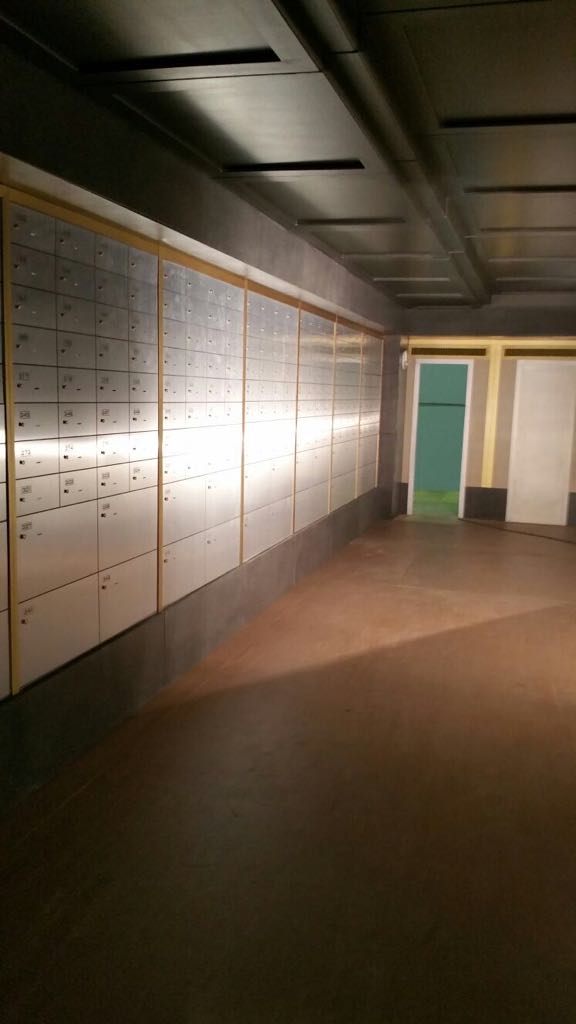 Un largo pasillo con muchos casilleros y una puerta verde.