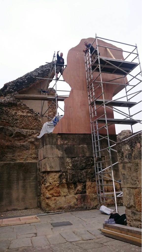 Un grupo de personas está de pie sobre un andamio frente a un edificio.