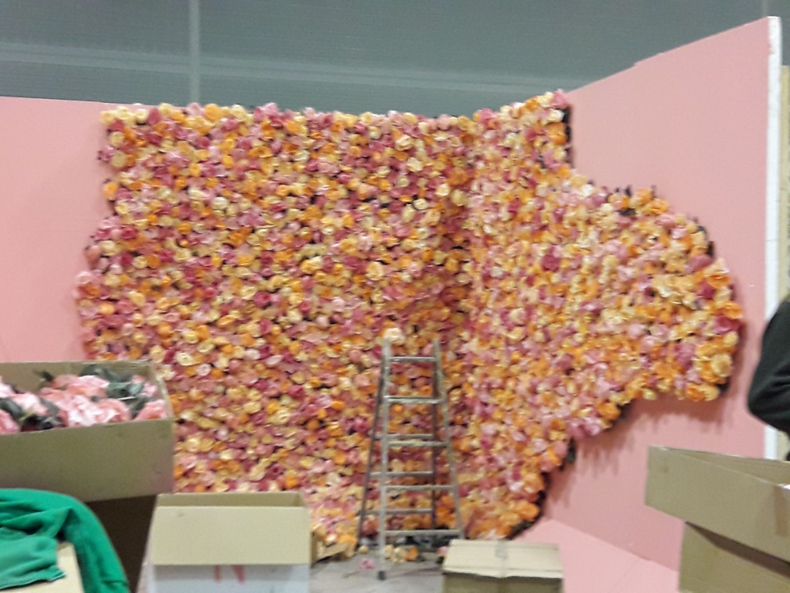 Una persona está parada frente a una pared de flores.