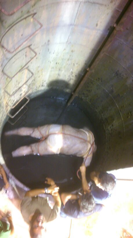 Un grupo de personas está de pie alrededor de un hombre tendido en un pozo.