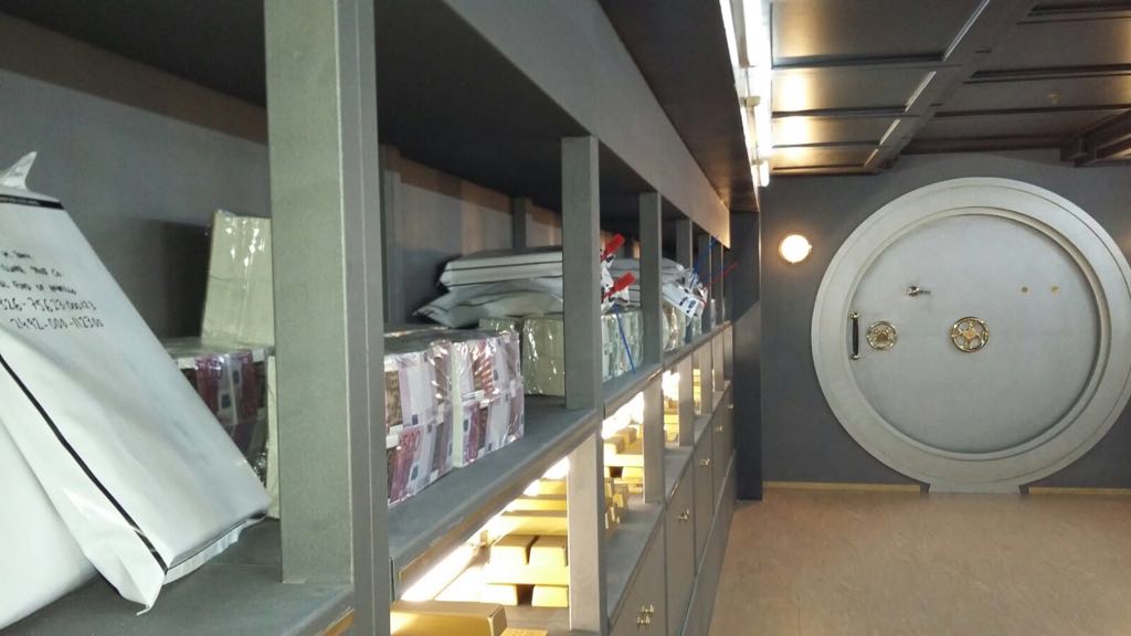 Una habitación con estantes y una puerta redonda que parece una bóveda.