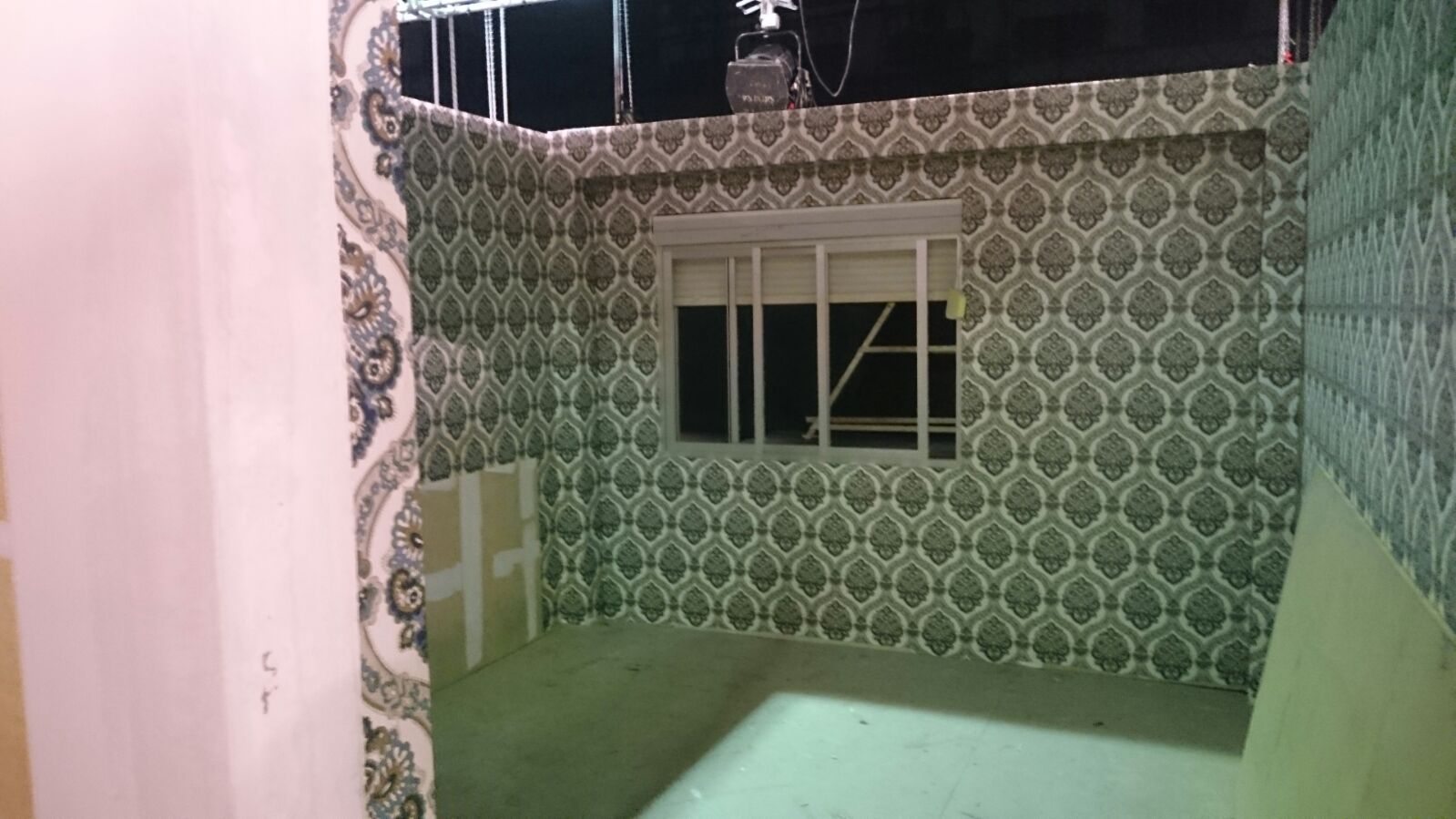 Una habitación con una pared estampada y una ventana.