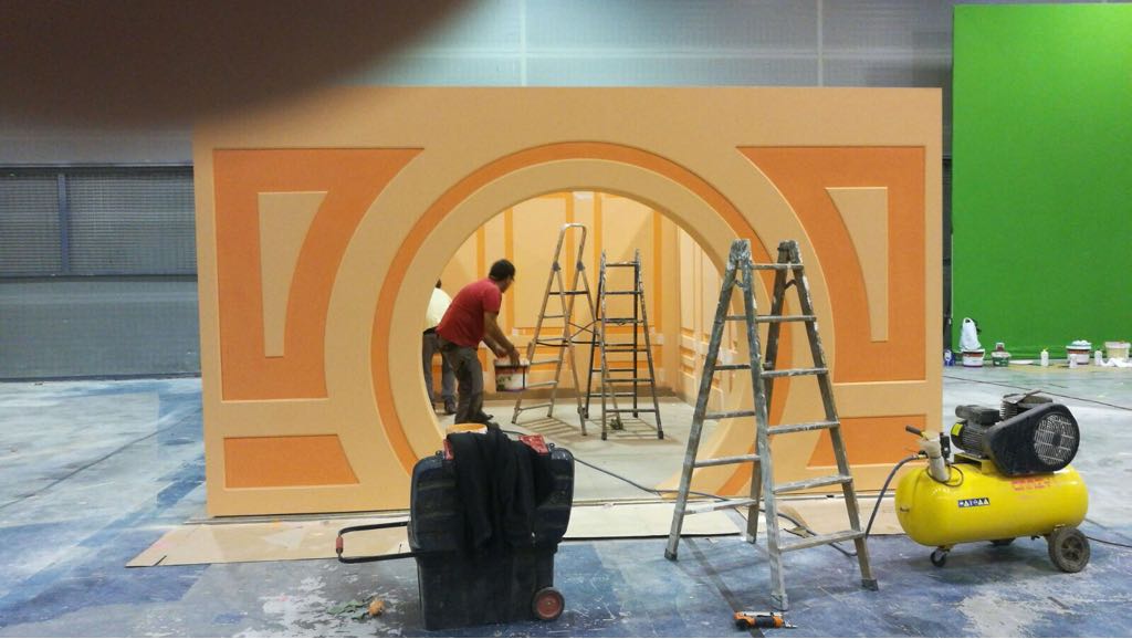 Un hombre está parado frente a una pared con una escalera y un compresor de aire amarillo.