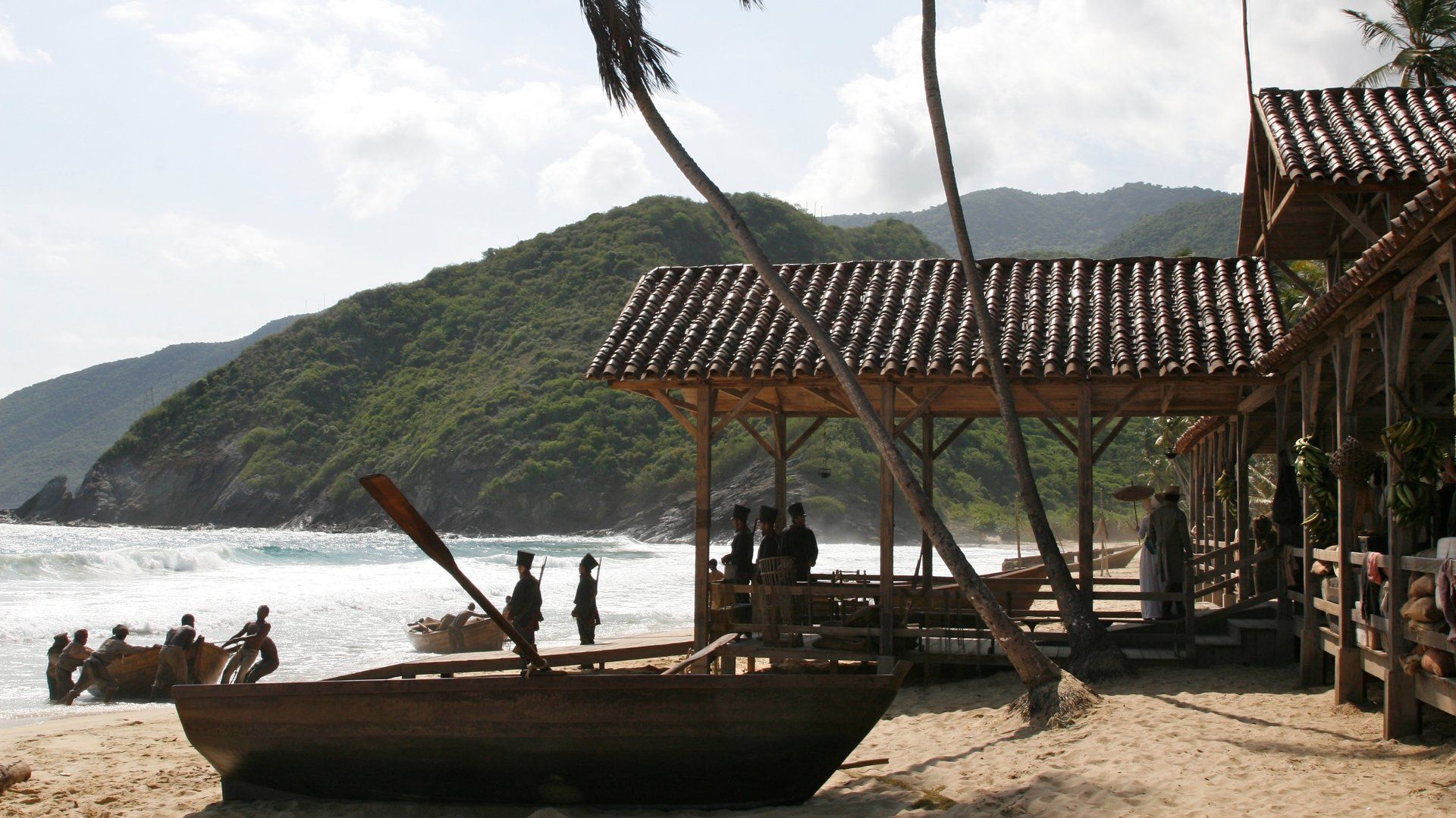 Un grupo de personas de pie en una playa con un barco en primer plano.