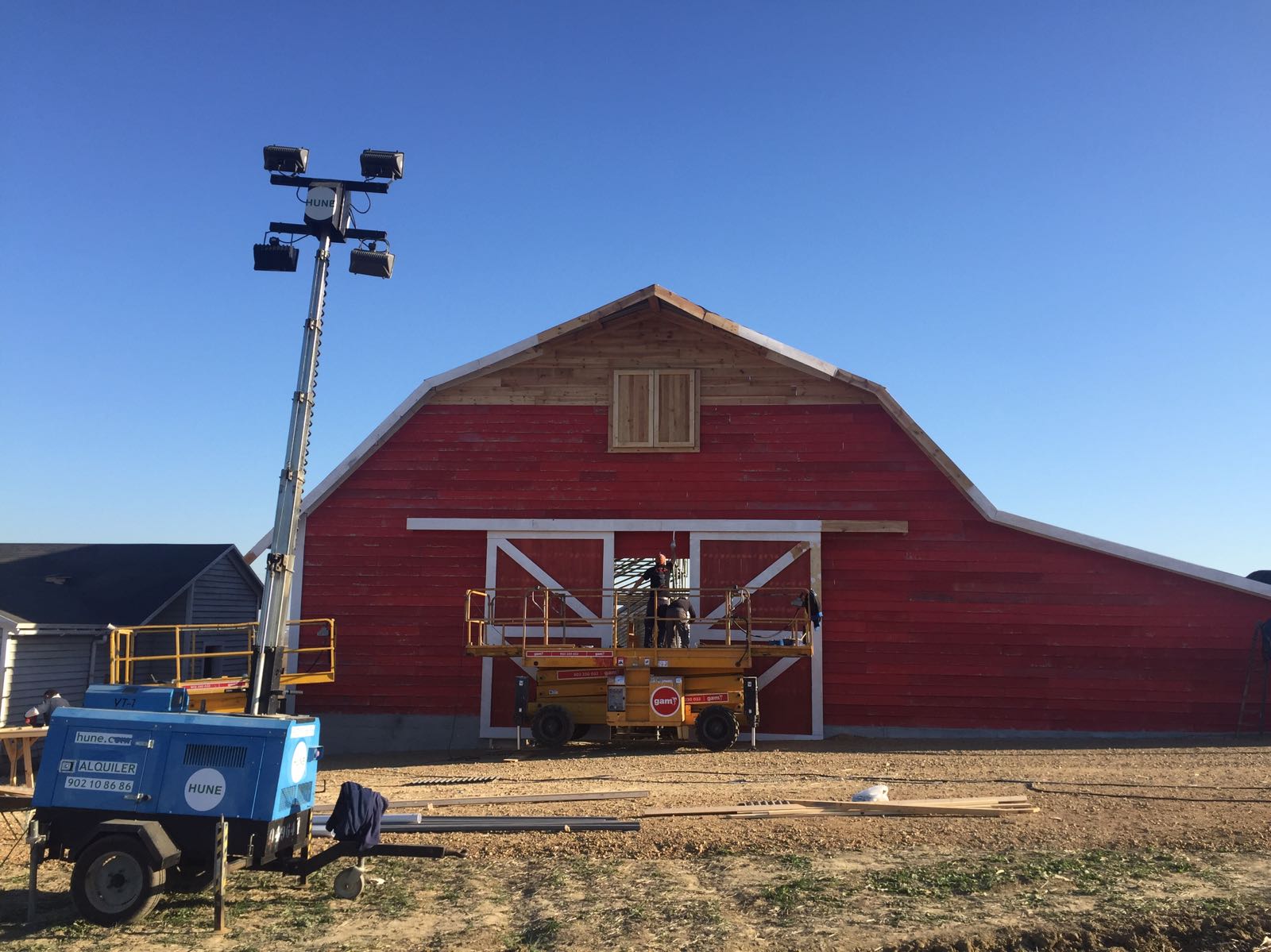 Se está construyendo un granero rojo grande en un campo de tierra.