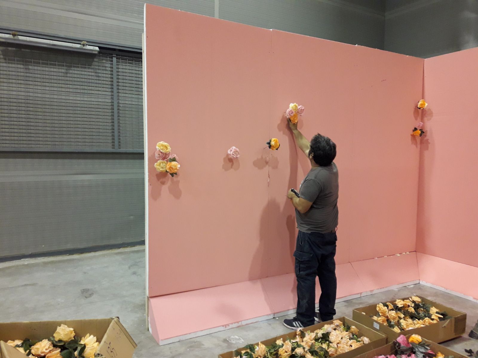 Un hombre está poniendo flores en una pared rosa.