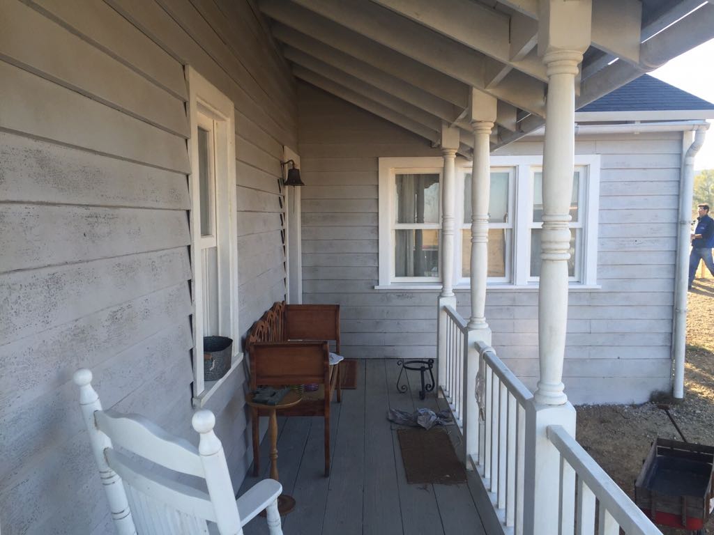 Una mecedora blanca se encuentra en el porche de una casa.