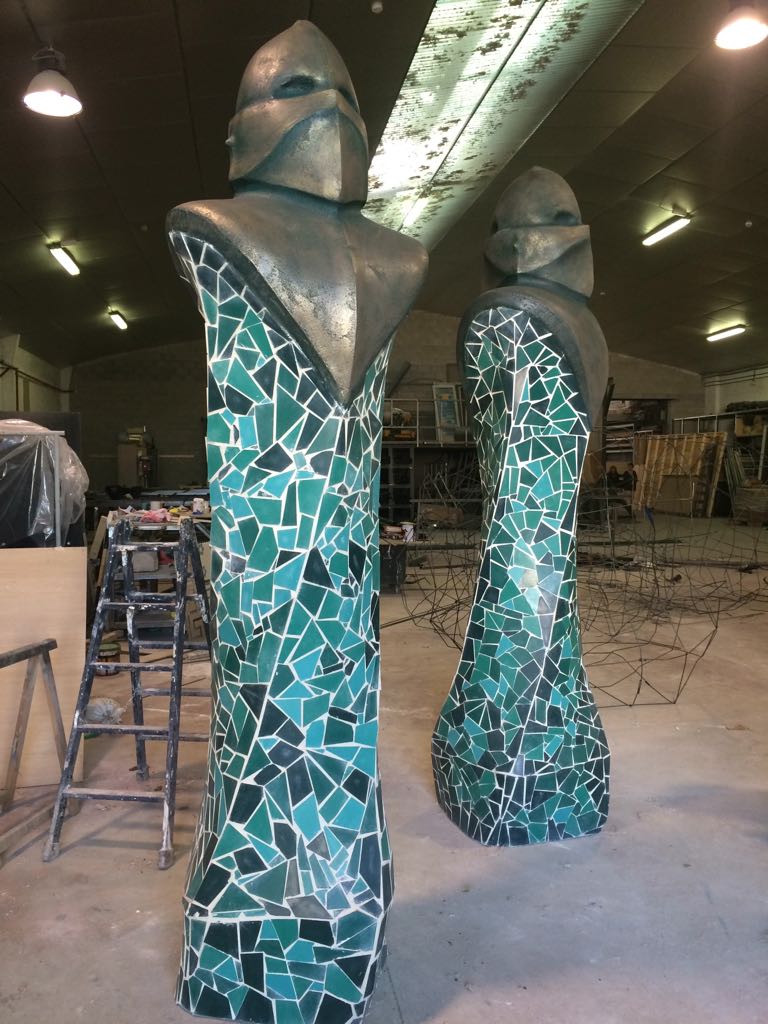 Dos estatuas en una habitación con una escalera al fondo.